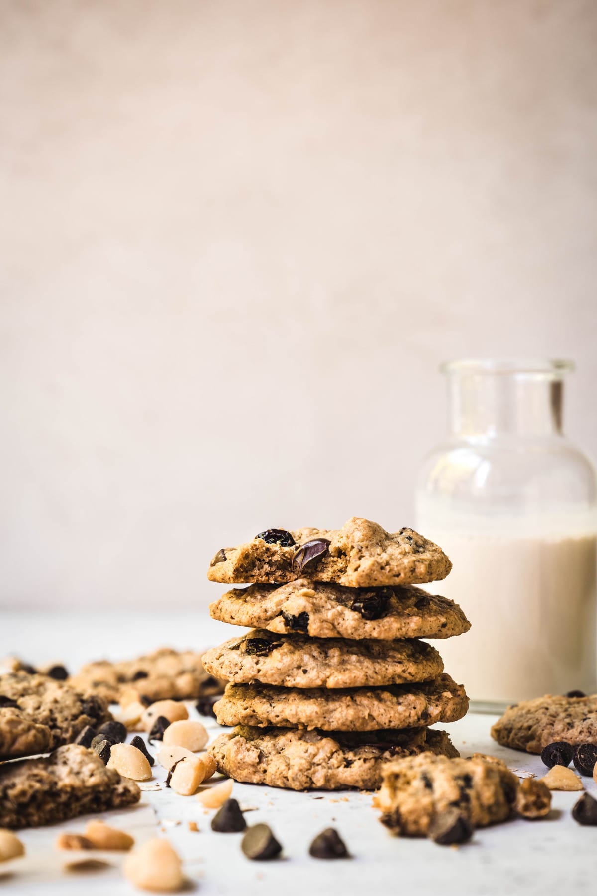 Side view of stack of chocolate chip cherry cookies with macadamia nuts with milk in background