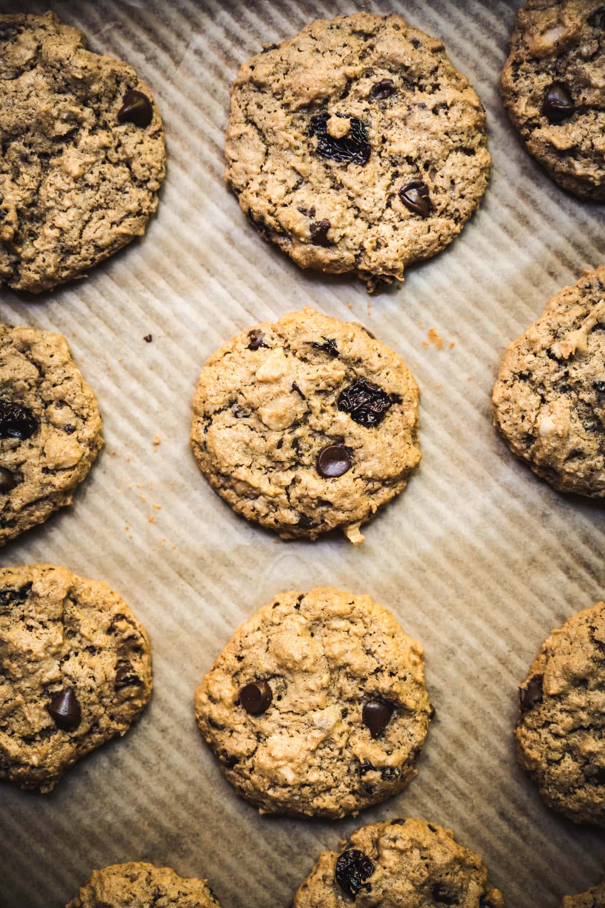 Overhead view of chocolate chip cherry cookies with macadamia nuts on parchment paper-lined tray