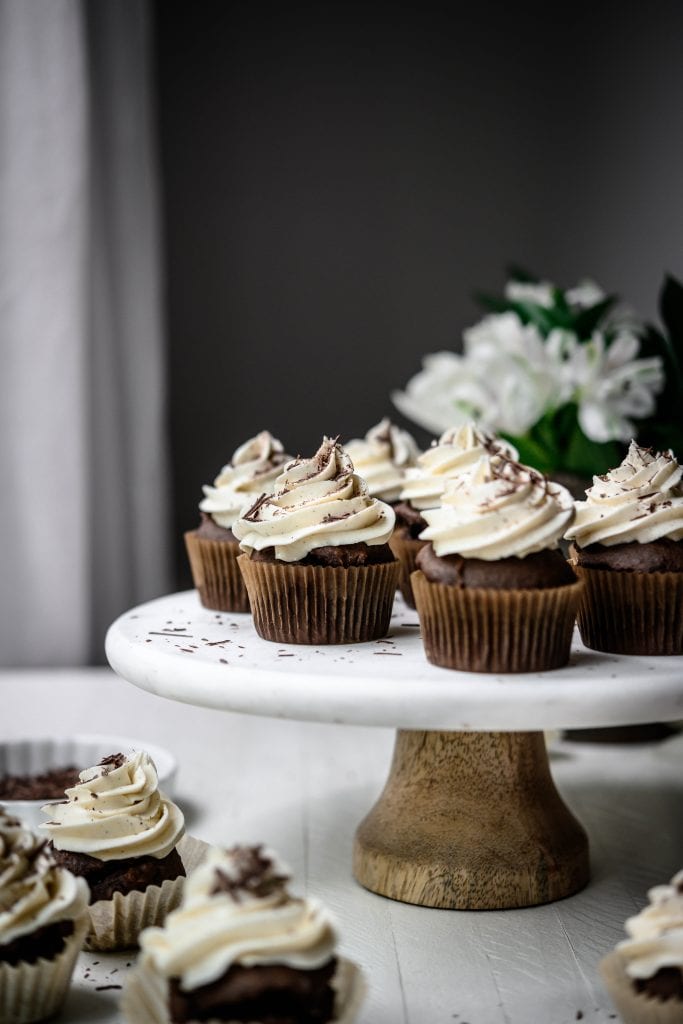 Side view of vegan chocolate cupcakes on a white marble cake platter