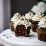 Side view of vegan chocolate cupcakes with vanilla frosting with bite taken out