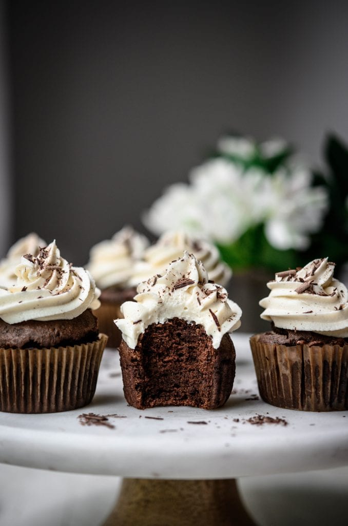 Side view of vegan chocolate cupcakes with vanilla frosting with bite taken out