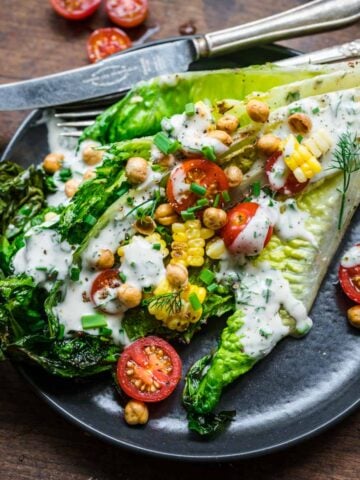 Overhead view of grilled romaine with tomatoes and ranch dressing.