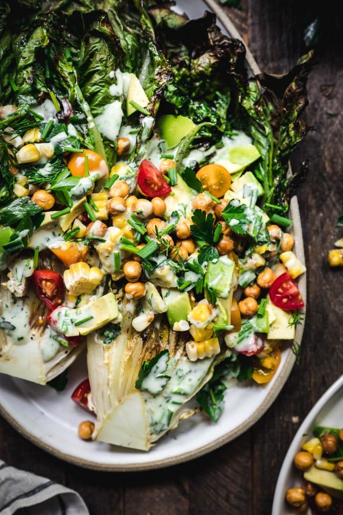 overhead of grilled romaine salad with vegan ranch, crispy chickpeas, grilled corn and avocado