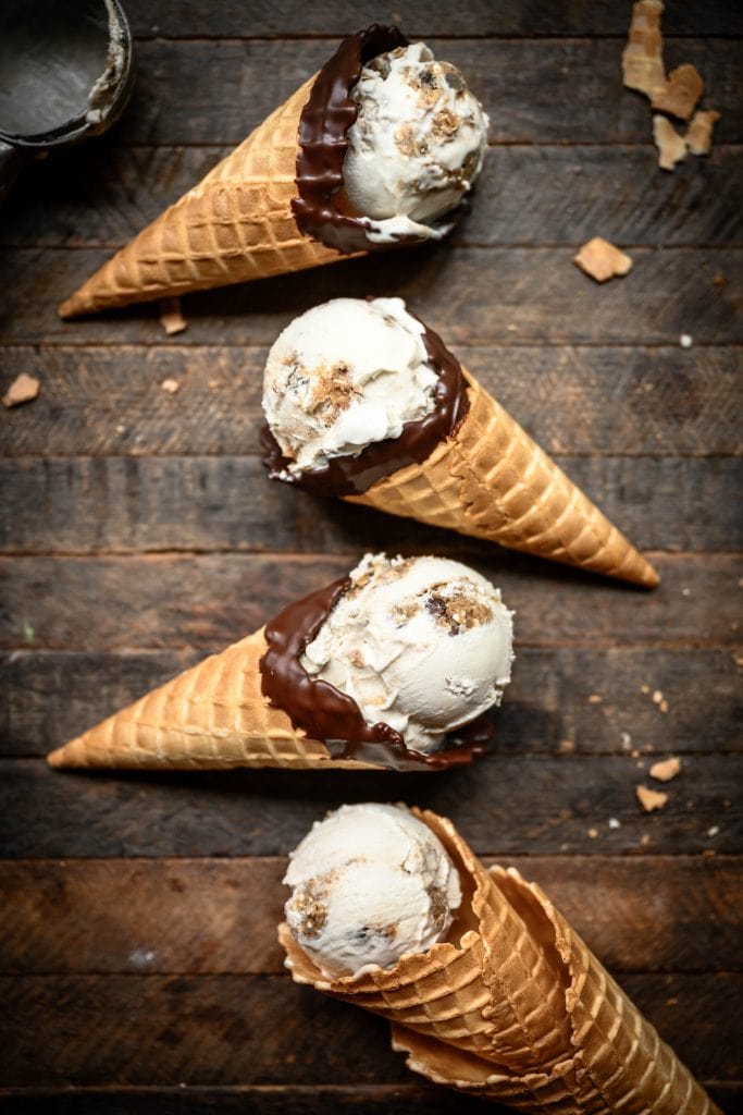 Overhead view of cookie dough ice cream in chocolate-dipped cones on wood background
