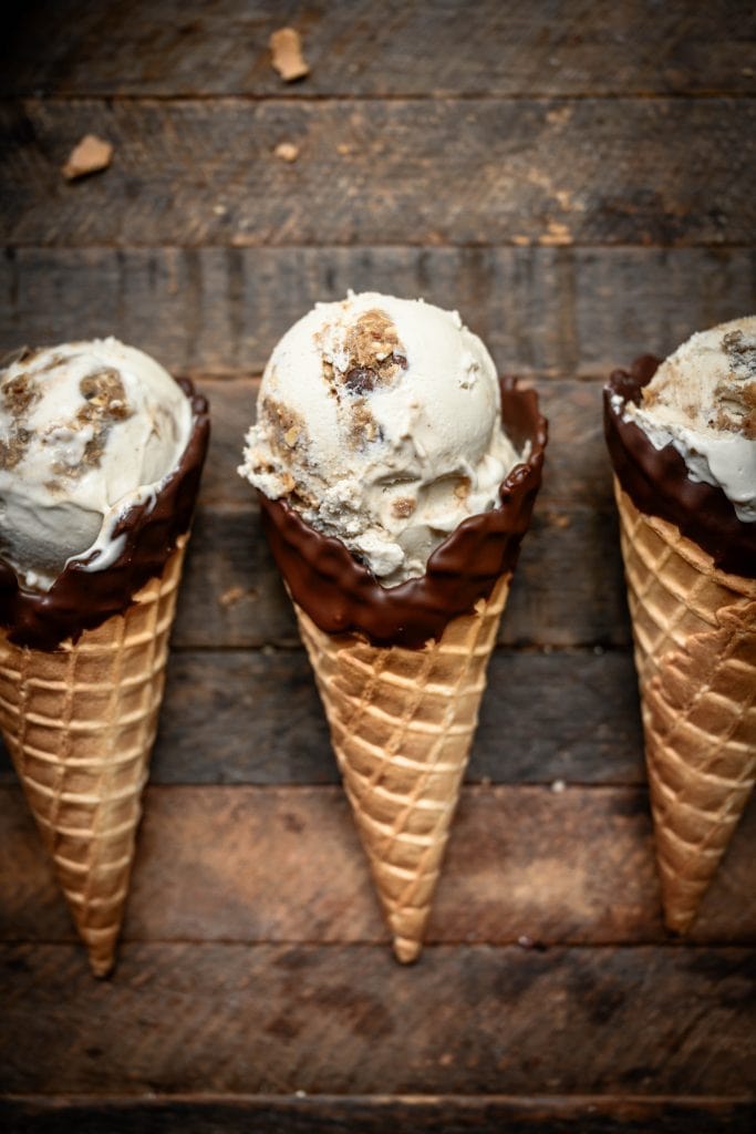 Overhead view of cookie dough ice cream in chocolate-dipped cones on wood background