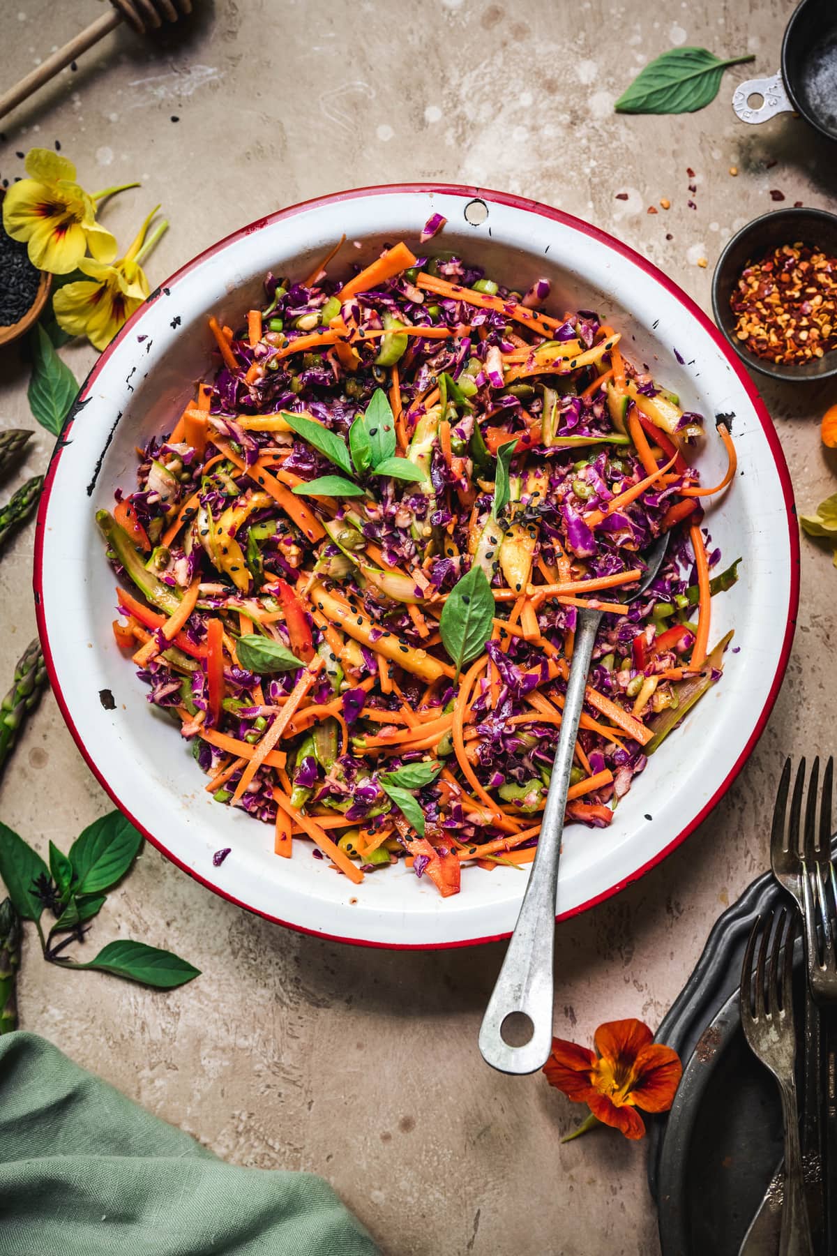 Overhead view of rainbow veggie slaw in a white bowl with antique spoon