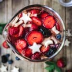 overhead of berries in 4th of july sangria in a glass pitcher
