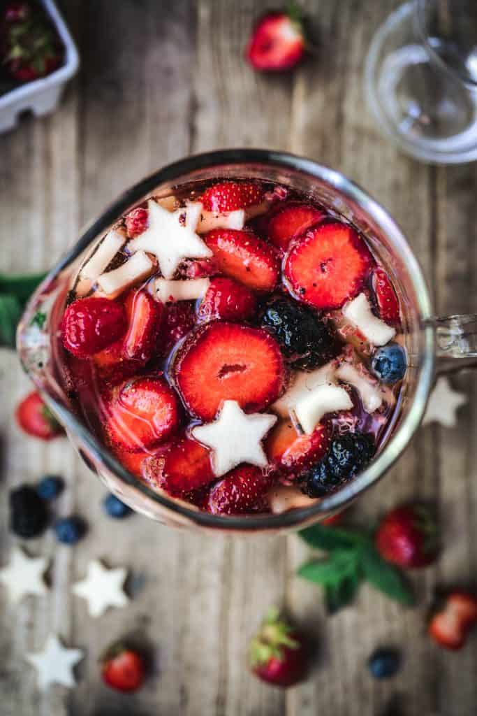 overhead of berries in 4th of july sangria in a glass pitcher