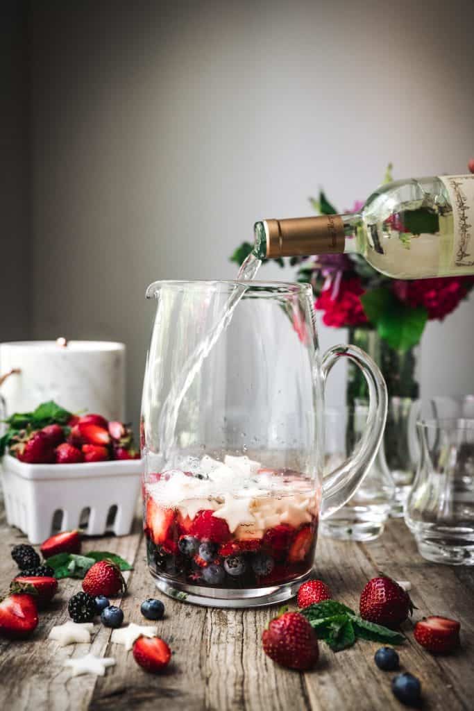 side view of berries to make sangria in a glass pitcher