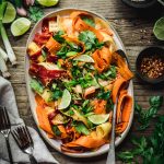 Overhead view of shaved rainbow carrot salad on a platter on rustic wood table