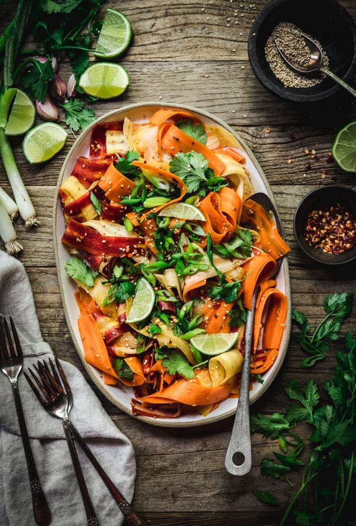 Overhead view of shaved rainbow carrot salad on a platter on rustic wood table