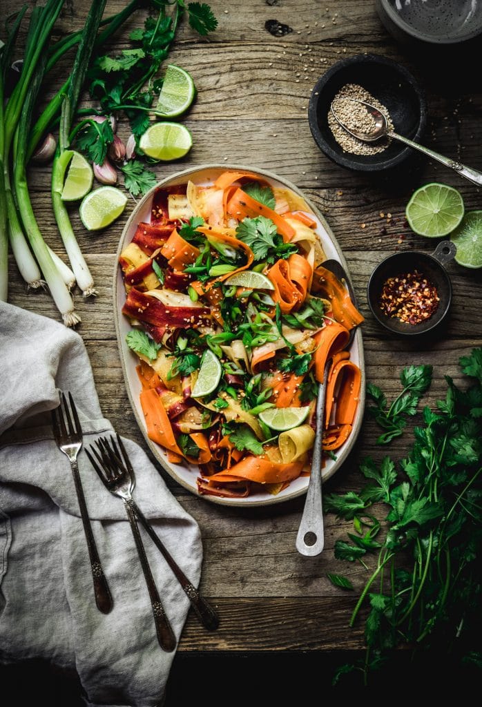 Overhead view of shaved rainbow carrot salad on a platter on rustic wood table