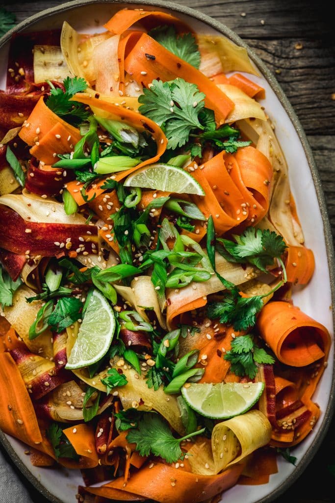 Close up Overhead view of shaved rainbow carrot salad on a platter on rustic wood table
