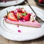 Side view of slice of vegan strawberry mousse pie on a white plate with fork