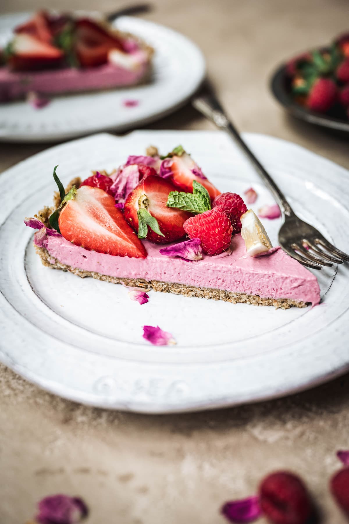 Side view of slice of vegan strawberry mousse pie on a white plate with fork