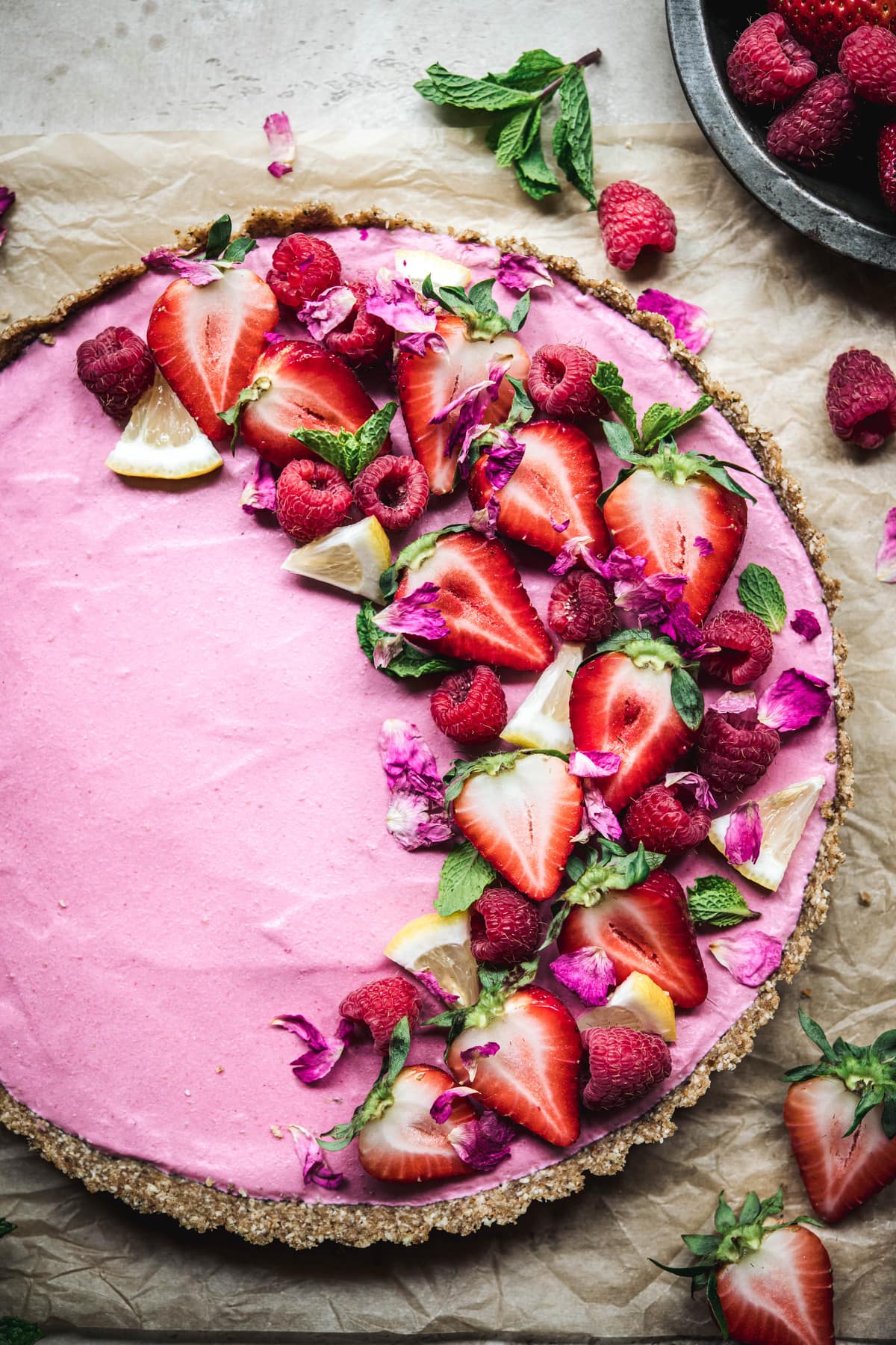 Overhead view of vegan strawberry mousse tart garnished with fresh berries on parchment paper