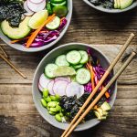 Overhead view of three vegan sushi bowls on wood table