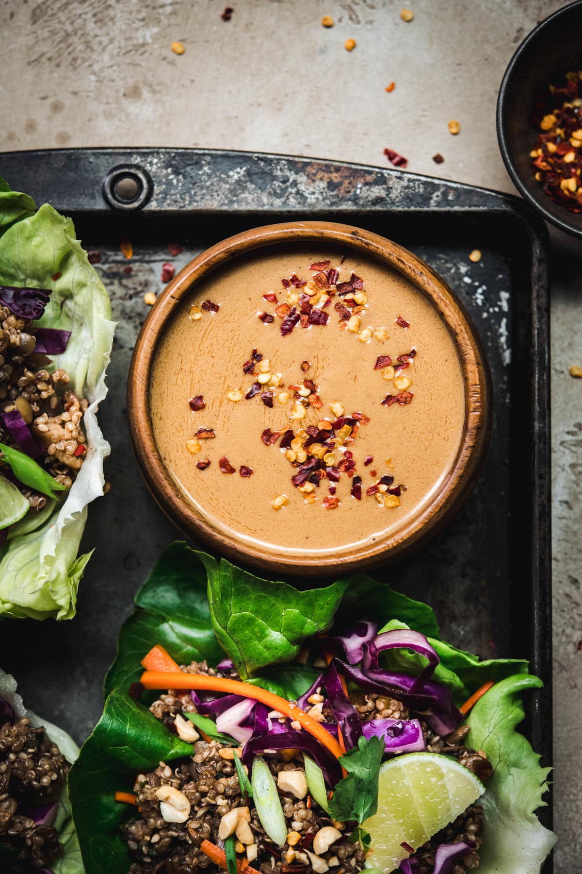 Overhead view of vegan spicy peanut sauce in wood bowl on antique tray to top vegan asian lettuce wraps
