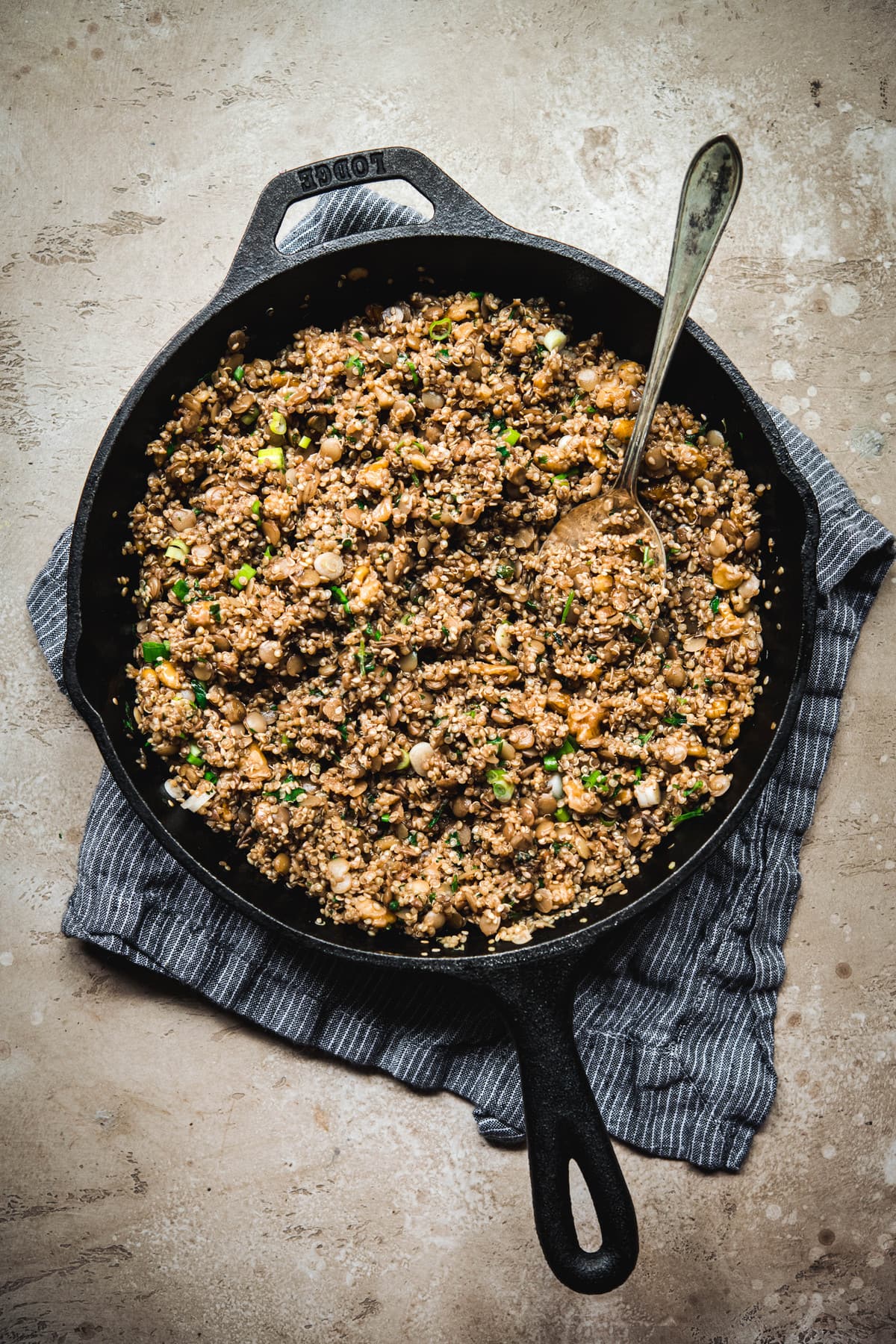 Overhead view of quinoa lentil walnut filling for vegan lettuce wraps in cast iron pan on rustic brown surface