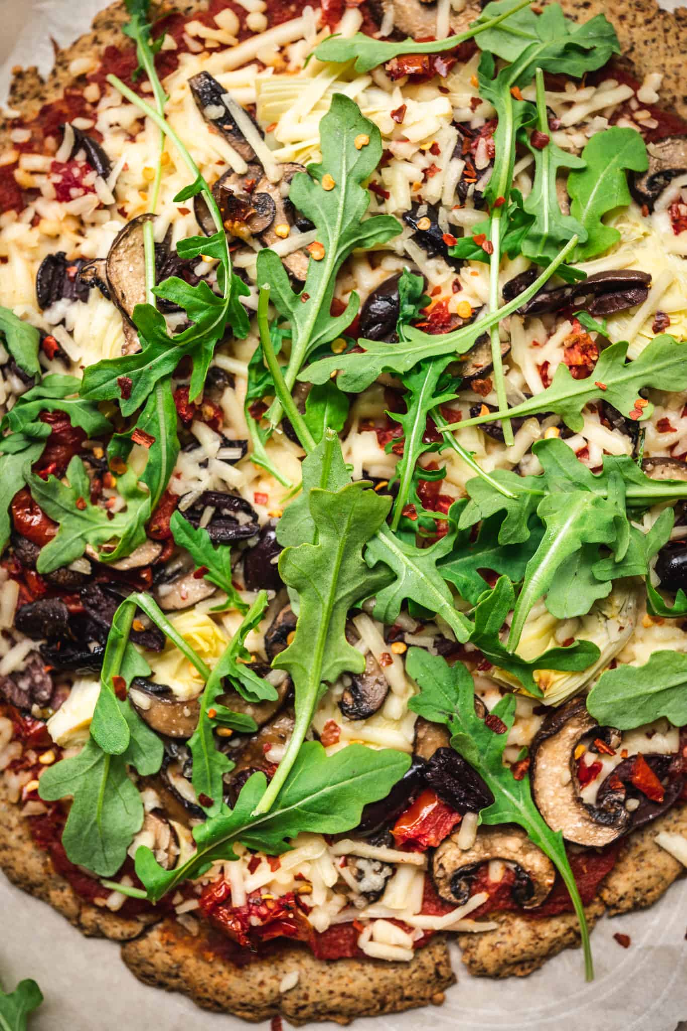 Close up view of pizza with mushrooms, arugula, artichokes and olives