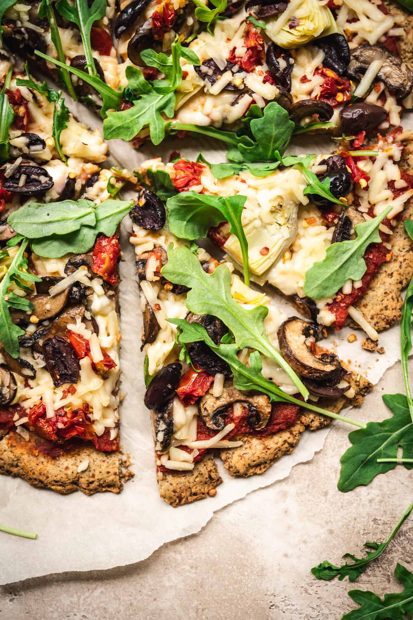 Close up overhead of a slice of pizza with vegan cauliflower crust and toppings