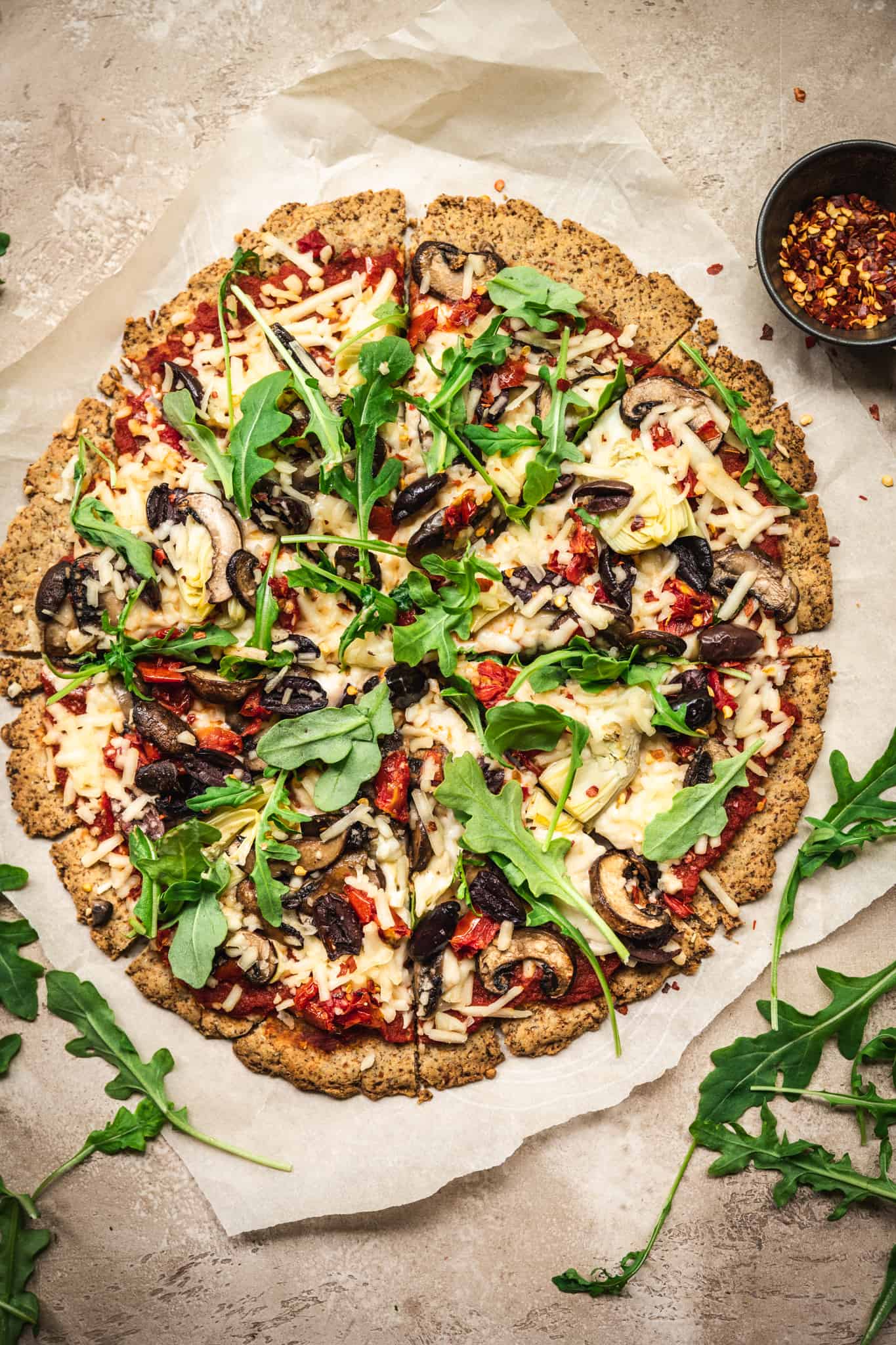 Overhead view of Crispy Cauliflower Vegan Pizza Crust with vegan pizza toppings on rustic background with white wine