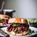 Side view of pulled mushroom sandwich with purple cabbage on a white plate