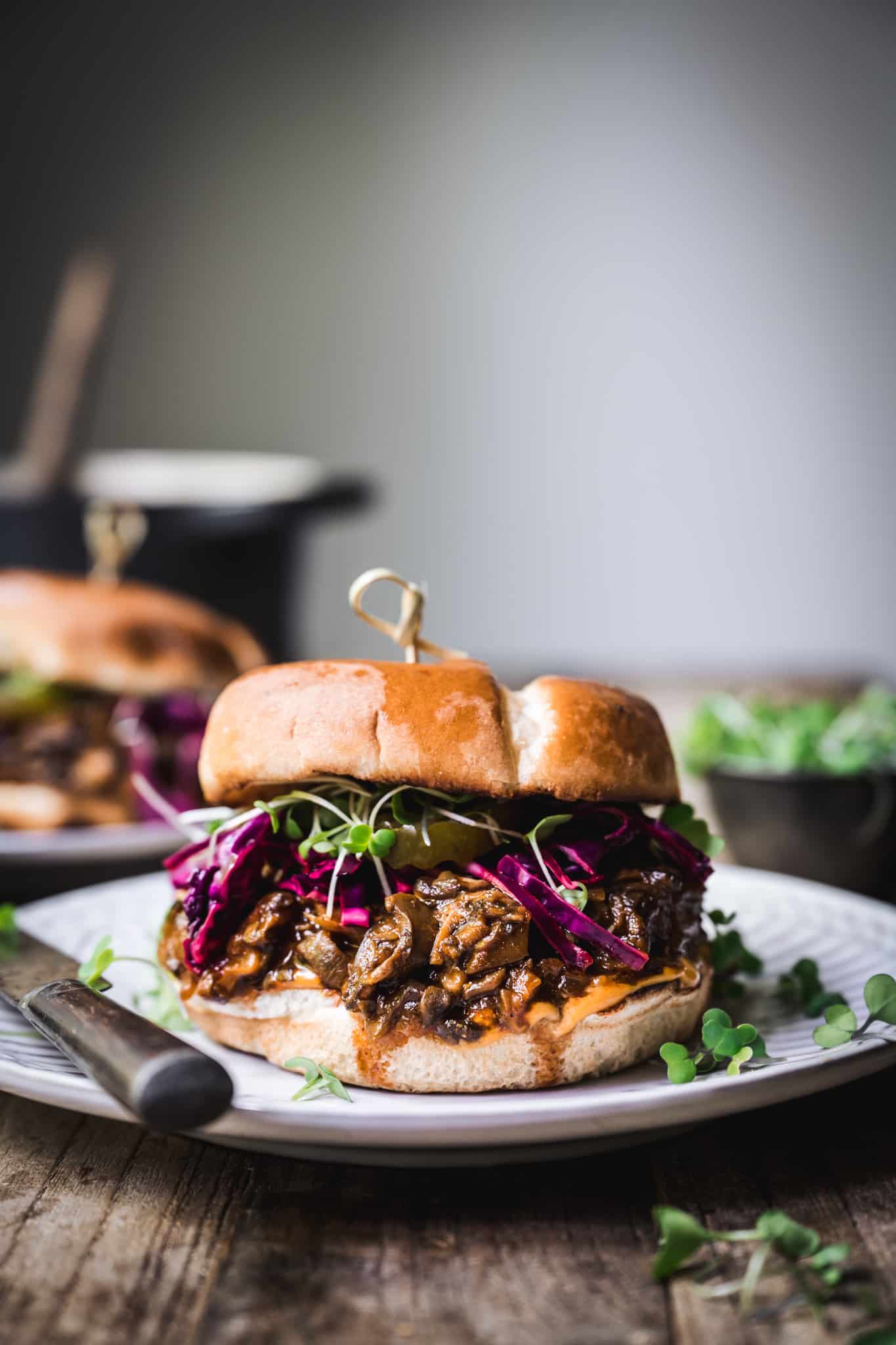 Side view of pulled mushroom sandwich with purple cabbage on a white plate