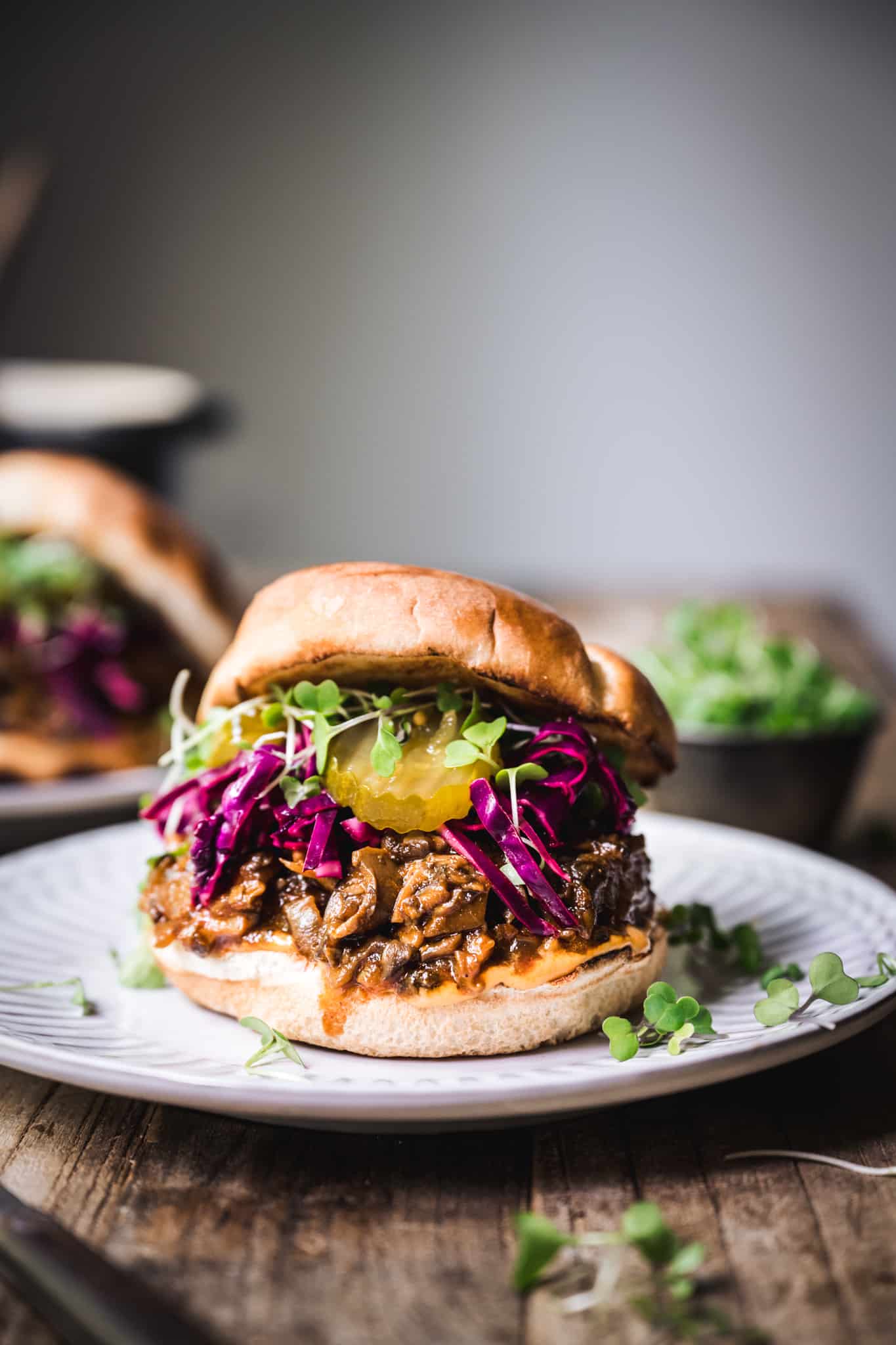 Side view of pulled mushroom sandwich with purple cabbage on a white plate
