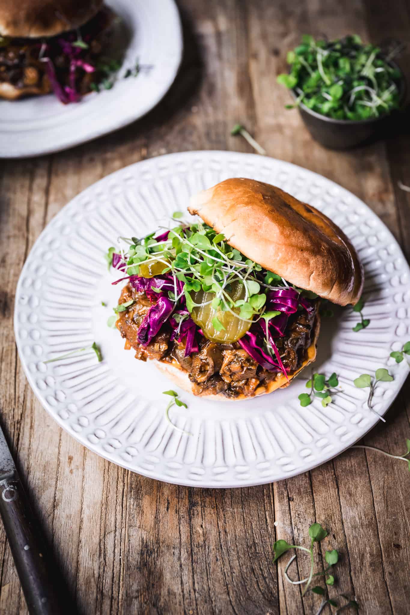 Side view of pulled mushroom sandwich with purple cabbage on a white plate