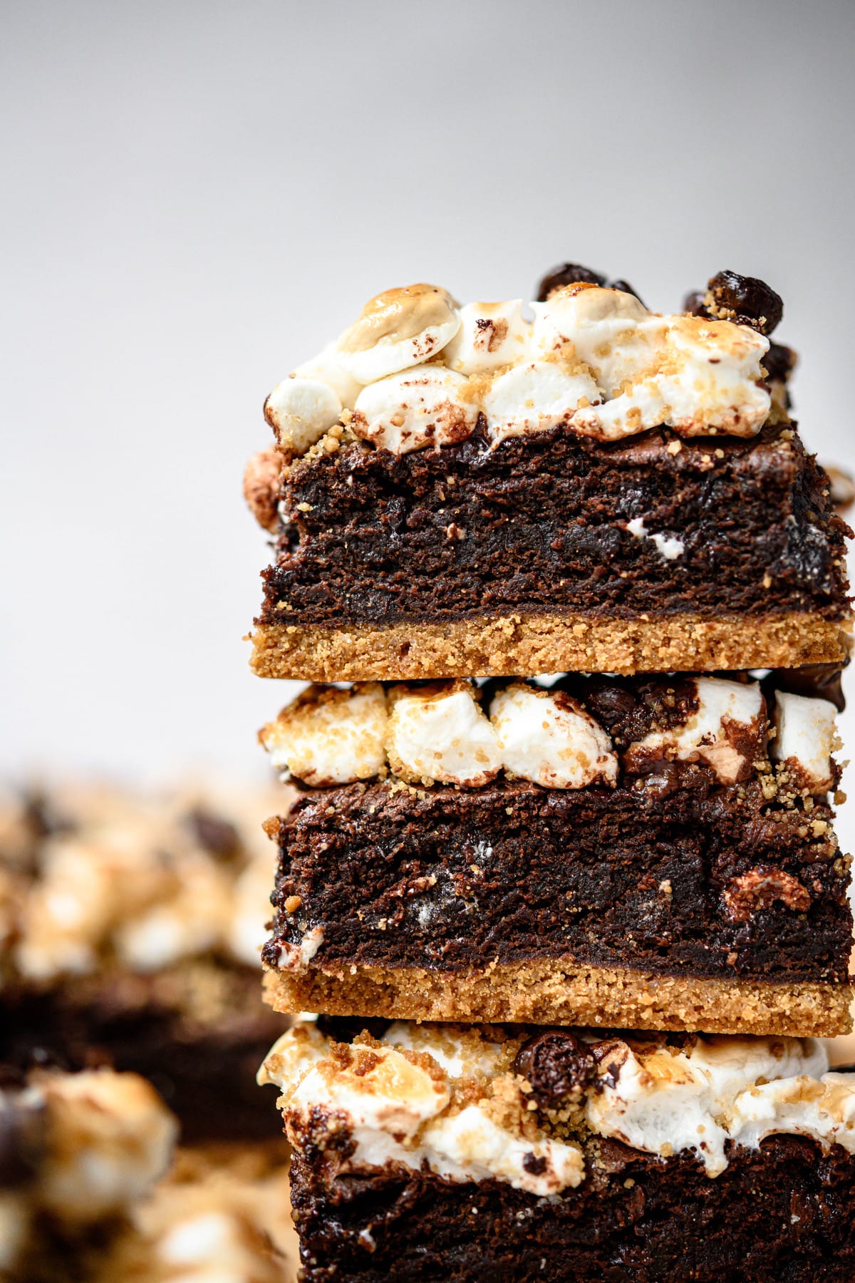 Close up Side view of three stacked vegan and gluten free s'mores brownies on parchment paper