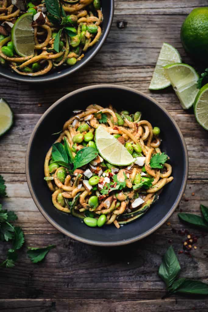 overhead of red curry almond butter zucchini nooodles in a bowl with lime slices