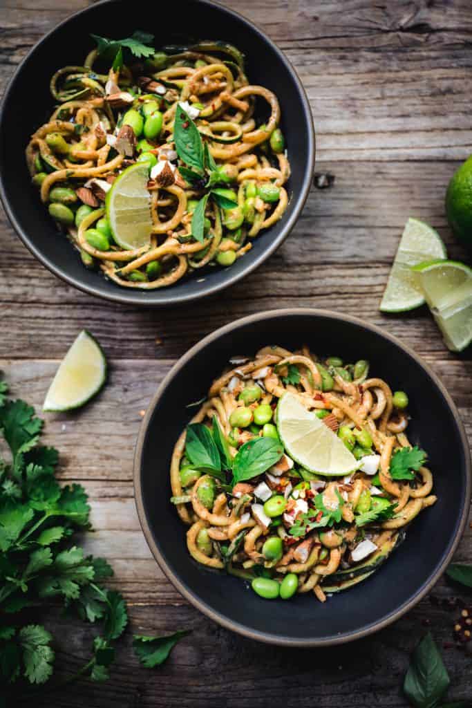 overhead of red curry almond butter zucchini nooodles in a bowl with lime slices