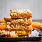 4 stacked apricot crumble bars on a tray.