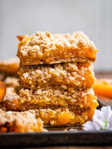 4 stacked apricot crumble bars on a tray.