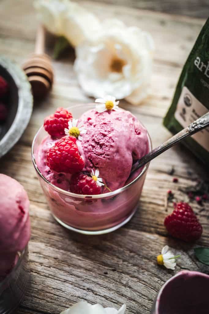 Overhead view of raspberry green tea infused ice cream in small glass jars on wood table