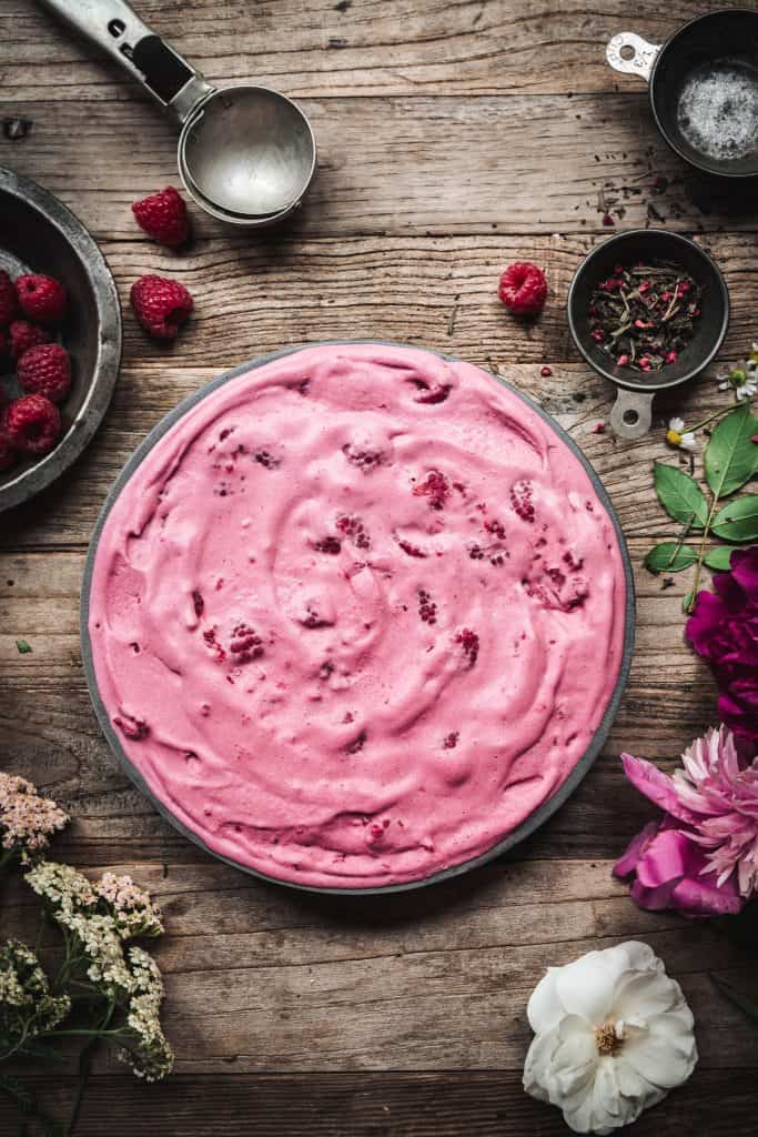 Overhead view of raspberry green tea ice cream in a circular pan on wood table