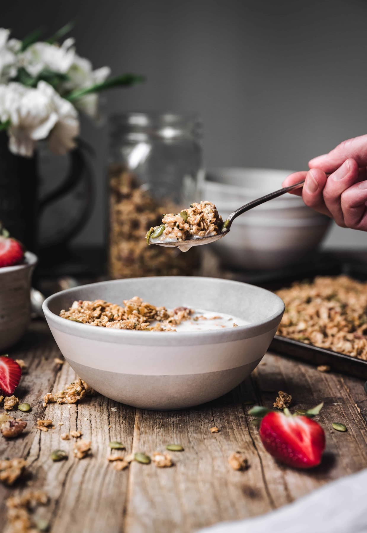 Person holding spoon of granola over bowl