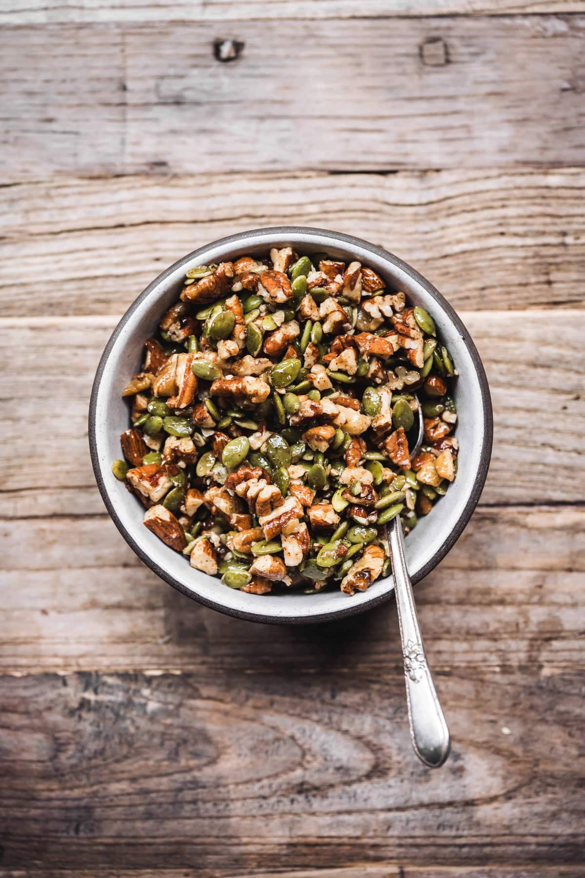 overhead view of pumpkin seeds and pecans in small bowl