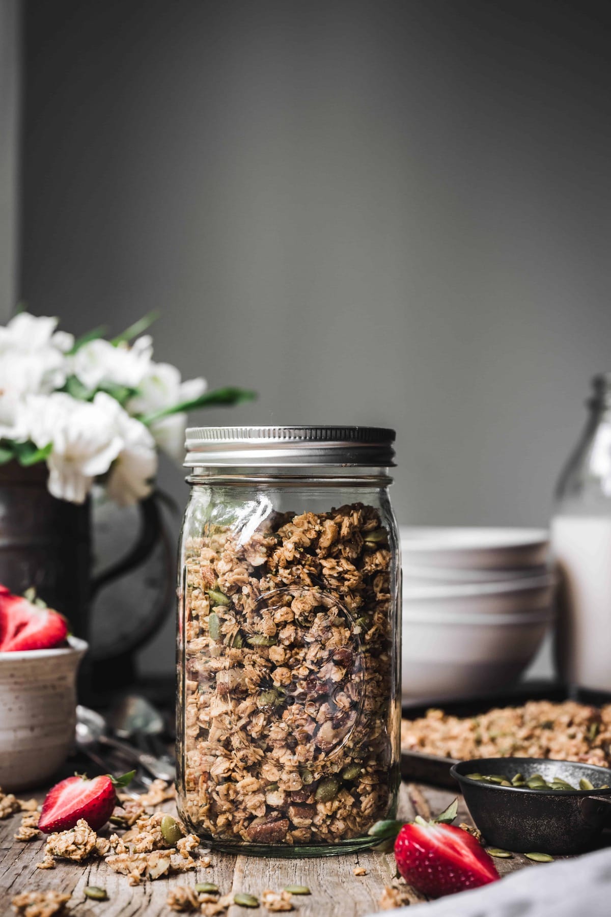 Side view of homemade granola in a glass jar on wood table