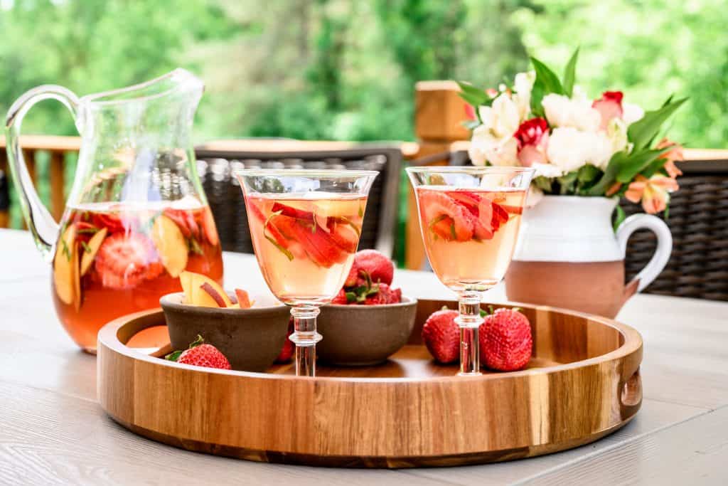 Side view of summer sangria in cocktail glasses on wood tray