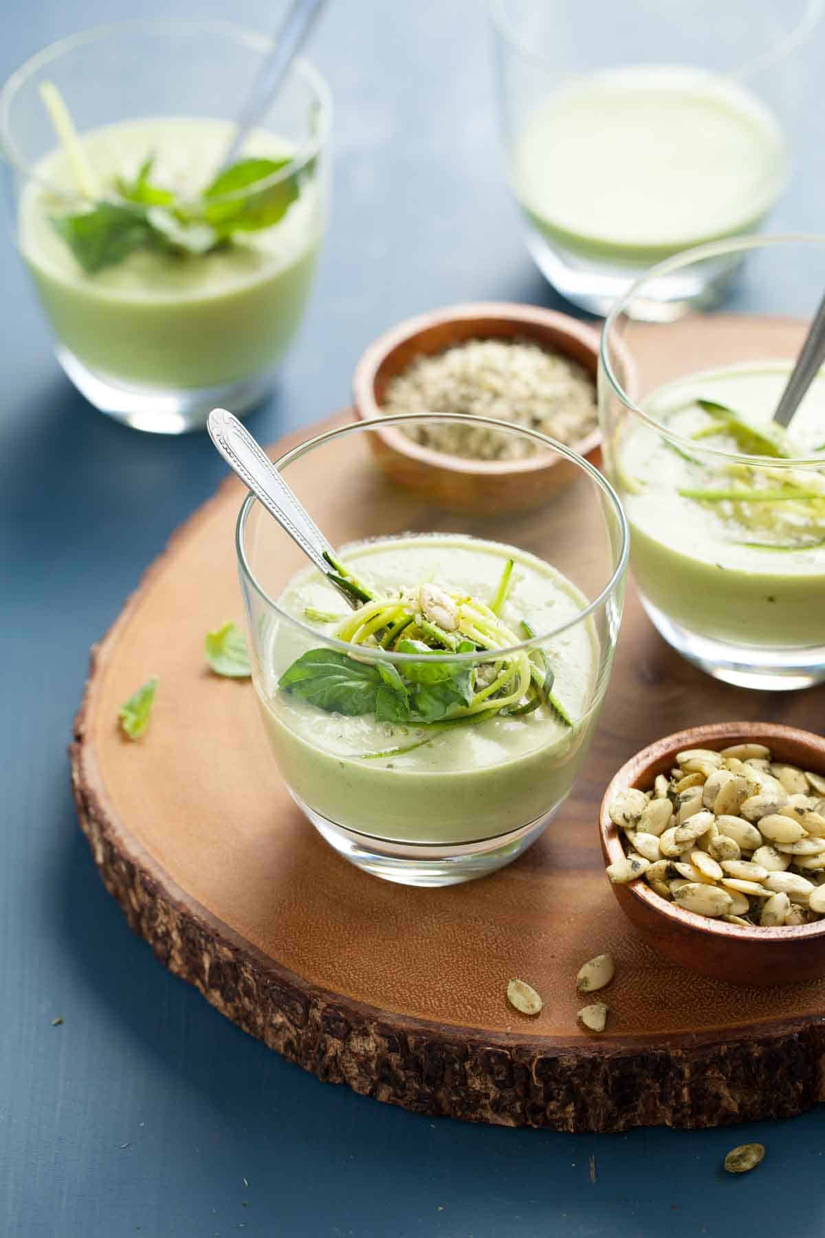 Chilled vegan zucchini basil soup in a small glass on a wooden board