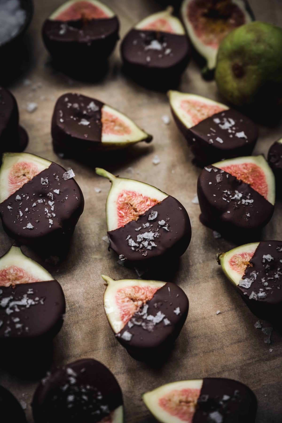 side view of dark chocolate dipped figs on parchment paper