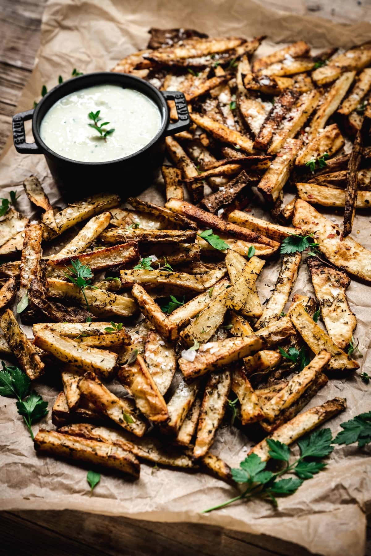 side view of super crispy oven fries with vegan aioli on parchment paper