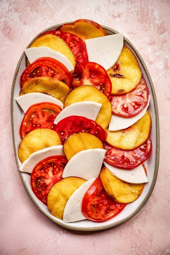 overhead of perfectly layered vegan caprese salad with grilled peaches and tomatoes