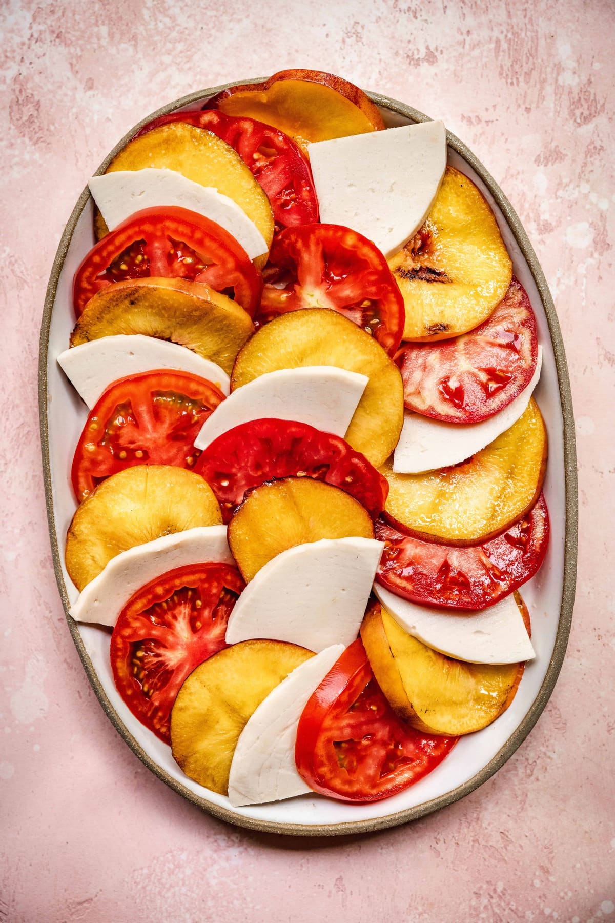 overhead of perfectly layered vegan caprese salad with grilled peaches and tomatoes