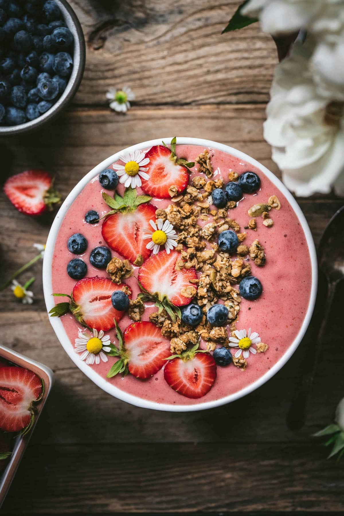overhead view of vegan strawberries and cream smoothie bowl topped with fresh fruit and granola