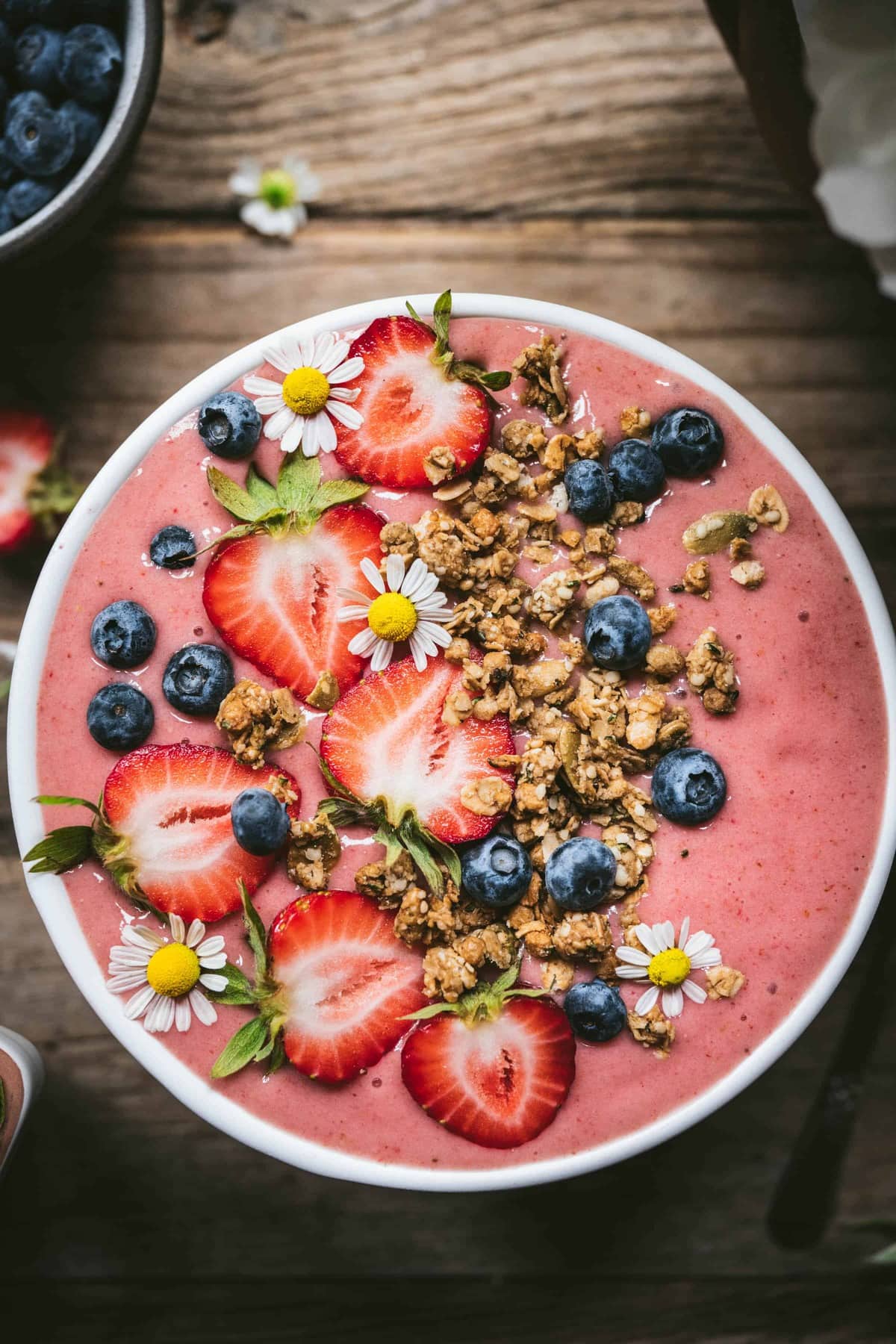 overhead view of vegan strawberries and cream smoothie bowl topped with fresh fruit and granola