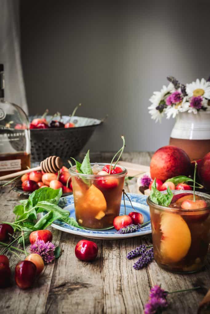 side view of bourbon peach smash cocktail on wood table