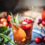 side view of bourbon peach smash cocktail on wood table